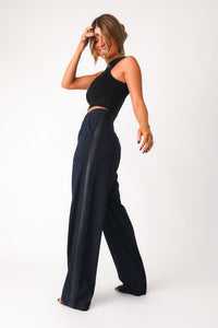 Full body side view iew of 'Bianca' navy trouser show casing black faux leather side seam panel detail and side pocket. Paired with black basics bra tank.