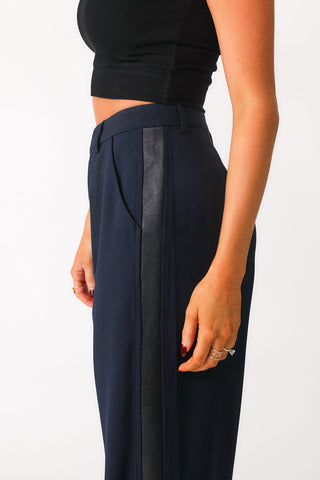 Close up side view of 'Bianca' navy trouser show casing black faux leather side seam panel detail and side pocket. Paired with black basics bra tank. 