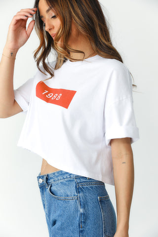 Side view: Model showcasing white oversized, crop tee with Red Block featuring "1988"