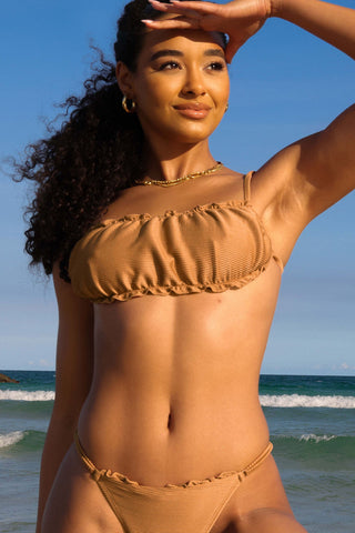 Model wearing Sandy Bikini, ribbed, golden material with ruffled edge detailing.